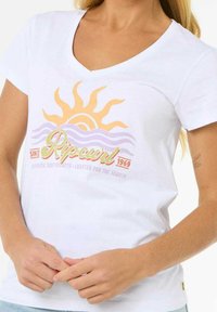 Hvid bomulds v-hals t-shirt med et farverigt sol- og bølgegrafik. Inkluderer grøn og orange tekst med mærkenavnet "Ripcurl."