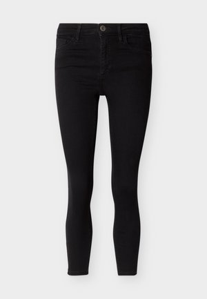 Μαύρο τζιν στενής εφαρμογής με κουμπί και φερμουάρ, μπροστινές και πίσω τσέπες, παρουσιάζεται σε απλό ανοιχτό φόντο.