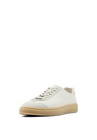 Weiße Sneaker mit einem glatten Obermaterial aus Leder, subtilen Nahtdetails, einer abgerundeten Zehenpartie und einer beigen Gummisohle. Die Schnürsenkel sind durch fünf Ösen gefädelt.