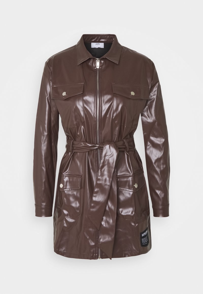 Veste longue à manches longues en simili cuir marron avec fermeture éclair à l'avant, ceinture à la taille, quatre poches à rabat avec boutons et un petit patch noir près de l'ourlet.