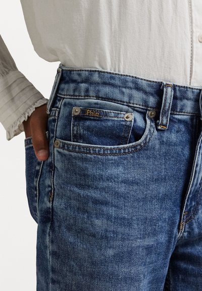 Light blue denim jeans with a five-pocket design, featuring contrasting stitching, a logo patch, and a slightly faded texture.