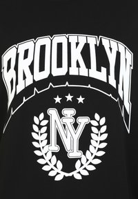 Černé tričko s výrazným bílým textem "BROOKLYN" a "NY" uvnitř vavřínového věnce, s dvěma hvězdami nad designem.