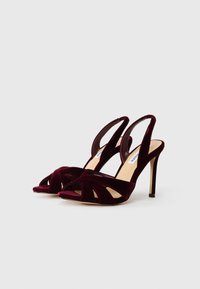 Bordo baršunasti natikači s visokom potpeticom i prelaznim trakama. Glatka tekstura i otvoreni dizajn s prstima.