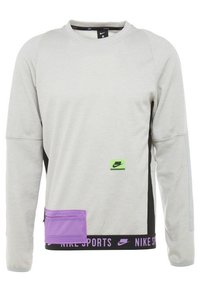 Sweatshirt gris clair à manches longues, col côtelé, panneaux latéraux noirs, poche zippée violette et logo Nike vert sur le devant.