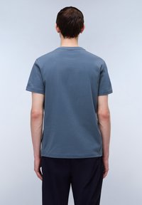 Camiseta de manga corta en algodón de color azul claro, con cuello redondo y un corte relajado. La vista trasera muestra un tejido suave y un diseño simple.
