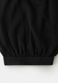 Tela de punto negra con detalle de cinturilla elástica fruncida sobre fondo blanco.