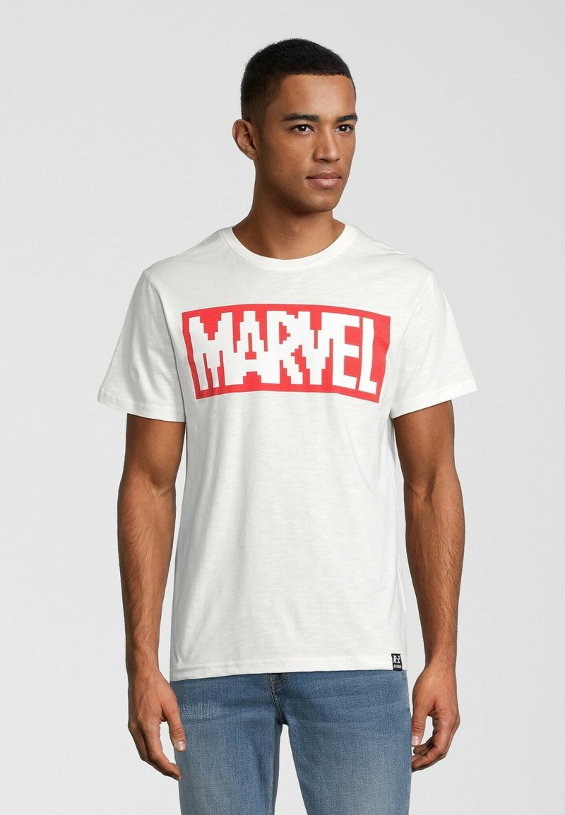Hvid bomulds t-shirt med et fedt rødt "MARVEL" logo i pixeliseret skrifttype. Har rund hals og korte ærmer. Bæres med blå jeans.