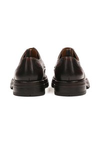 Zapatos de cuero marrón oscuro con un acabado suave, costuras detalladas, puntera redondeada y un tacón bajo y texturizado.