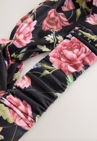 Schwarzes Blumen-Haarband aus weichem Stoff mit pink-weißen Rosenmustern, gestaltet mit einem Knoten-Design und einem gerafften elastischen Band.