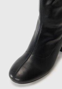 Botte de cheville en cuir noir avec un bout arrondi, une texture lisse, des détails de coutures verticales et un talon bloc de hauteur moyenne.