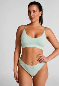 Mintgroene geribbelde bikini met een bralette-top met V-hals en dunne verstelbare bandjes, gecombineerd met bijpassende low-rise broekjes. Soepele textuur.
