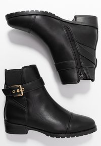 Botas negras hasta el tobillo de cuero suave, con cremallera lateral, una correa con un hebilla dorada y una suela de goma texturizada.