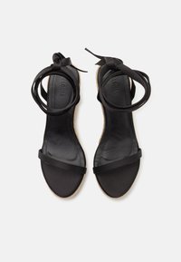Sandales espadrilles noires avec une tige en cuir lisse, des fines brides de cheville et une semelle tissée texturée. Aucune décoration visible.