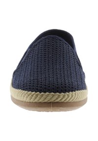 Zapato slip-on tejido en azul marino con ribete trenzado en beige y suela marrón claro, fotografiado de frente sobre un fondo blanco.