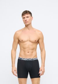 Čierne boxerky s elastickým pásom v šedým a čiernym vzorom, na ktorom je logo Nike. Materiál s elastickými vlastnosťami pre pohodlné nosenie a dobré prisadenie.