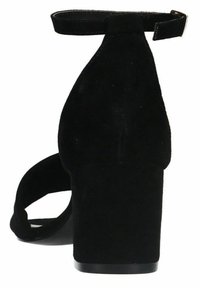 Black suede high heel shoe with an ankle strap, curved silhouette, and a chunky heel. The texture is soft, and the design is open-toed.