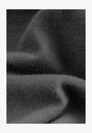 Ciemnoszara dzianina z drobnym, teksturowanym wzorem i miękkim, elastycznym układem, prezentująca zakrzywione fałdy i subtelną poświatę.