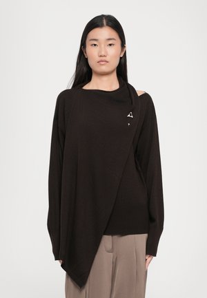Maglione marrone asimmetrico in un tessuto lavorato a maglia, con scollo drappeggiato e un accento metallico triangolare sul davanti.