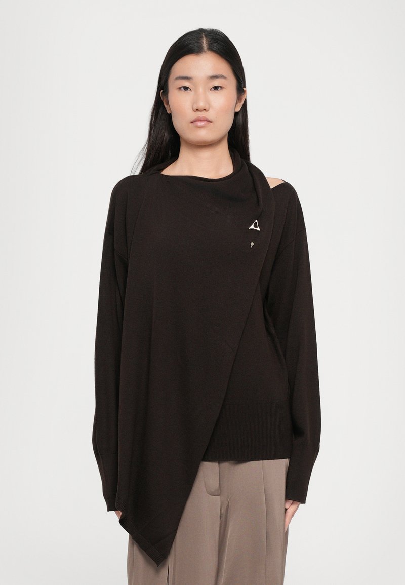 Brown asymmetric sweater in a textured knit featuring a draped neckline and a triangular metal accent on the front.