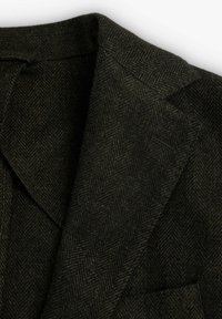 Blazer de lana en espiga verde oscuro con solapas y hombros con costuras visibles y cuello de muesca sobre un fondo blanco.