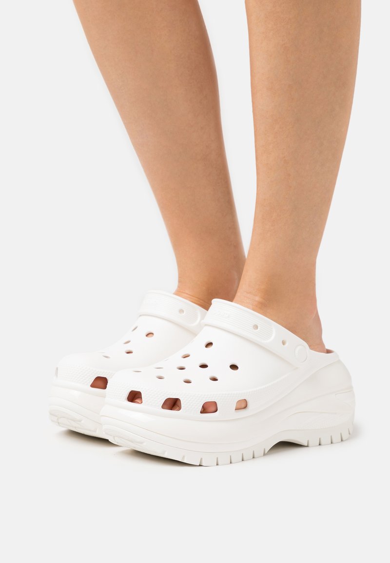 White clogs with ventilation holes, a textured band, and a slightly raised sole. Smooth material with a simple design and functional style.