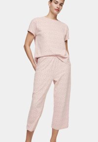 Conjunto de loungewear de color rosa claro con una parte superior holgada de manga corta y pantalones cortos. Presenta pequeños patrones de puntos negros en todo el conjunto.