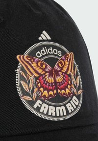 Czarna czapka z dużą, kolorową grafiką motyla, otoczoną elementami kwiatowymi oraz napisem "FARM RIO", z logo Adidasa powyżej.