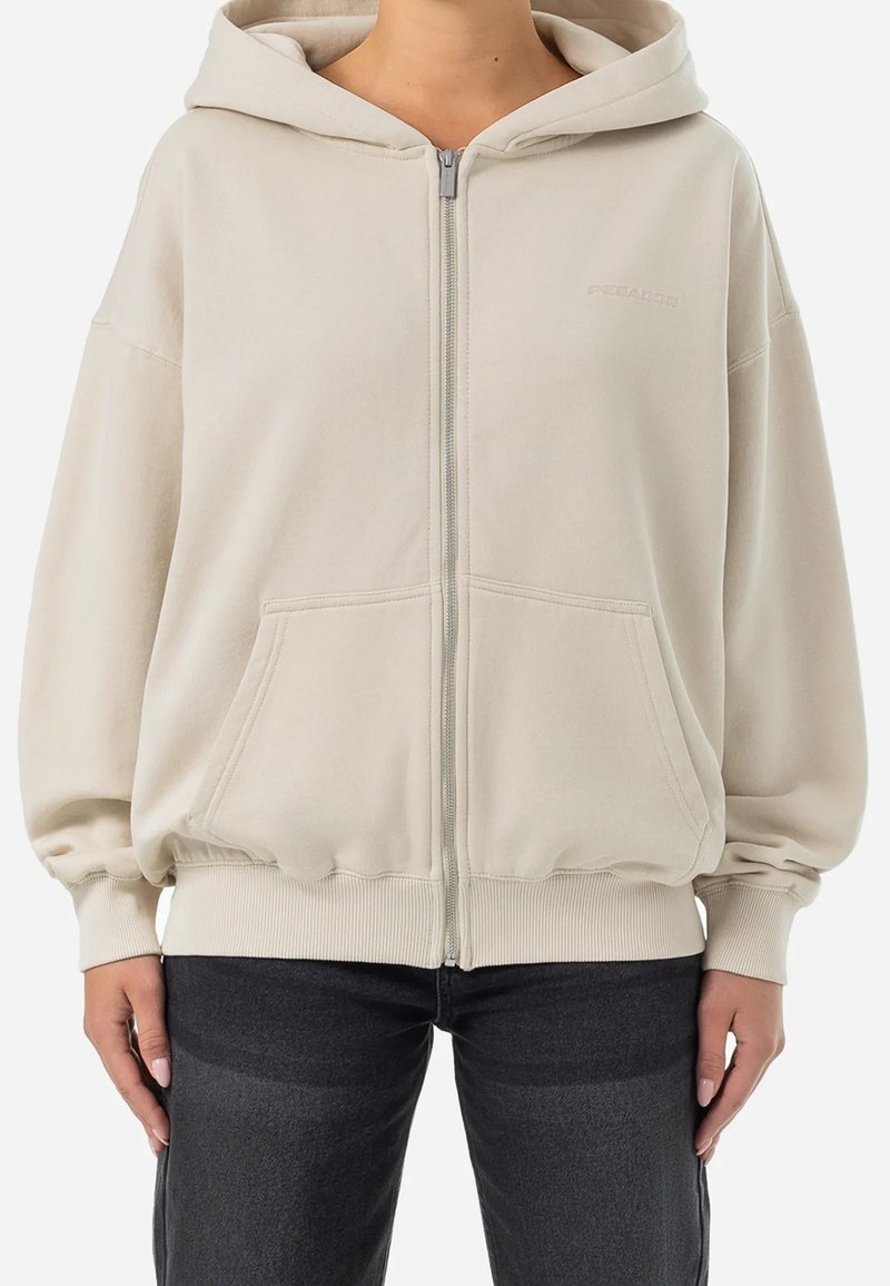 Beige zip-up hoodie i mjukt material; har en huva, oversize passform och framfickor med ribbad mudd och nederkant.