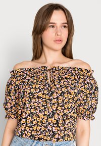 Blusa floral off-the-shoulder com base preta e flores laranjas e rosas, decote elástico e mangas bufantes, detalhe de abertura amarrada.