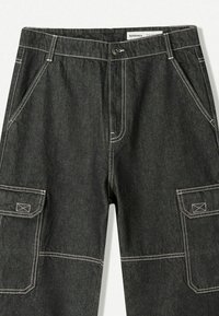 Zwarte denim cargo pants met witte steken, voorzien van zijzakken en een ritssluiting. Ontworpen voor functionaliteit en comfort.