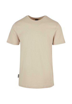Beżowy t-shirt z krótkim rękawem i okrągłym dekoltem, z małą czarną metką na lewym szwie bocznym na jednolitym białym tle.