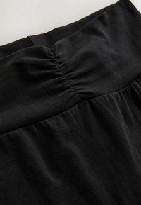 Schwarzer Stoffrock mit gerafftem Taillendetail, weicher Textur und fließender Silhouette. Einfaches und vielseitiges Design, das sich für verschiedene Outfits eignet.