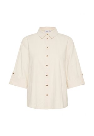 Chemise crème à manches courtes avec un col, un devant à boutons et des poignets retroussés. Elle présente des boutons marron sur un tissu texturé.