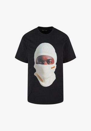 T-shirt nera con una grande grafica di una persona che indossa un berretto bianco e una sciarpa, con texture visibili nel cappello e nei tratti del viso.