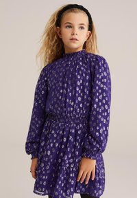 Ljubičasta haljina sa smirivanjem u struku, dugim napufdom rukavima i srebrnim životinjskim uzorkom. Mekana tkanina sa dizajnom suknje sa katovima.