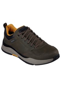 Sneaker in pelle marrone con accenti neri, superficie testurizzata, colletto imbottito e lacci. Suola flessibile con un dettaglio giallo vicino al tallone.