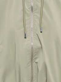 Veste beige clair devant avec une fermeture éclair argentée et des cordons beiges avec des embouts métalliques argentés.