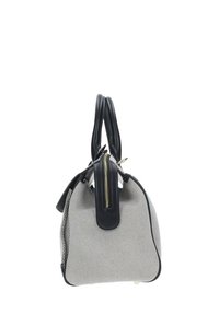 Borsa a mano in bianco e nero con motivo a righe, caratterizzata da una forma strutturata, manici in pelle e chiusura con zip. Presenta un accento nero a contrasto alla base.
