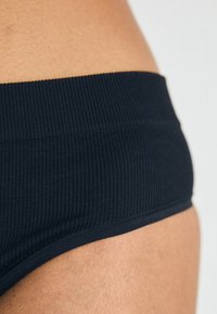 Zwarte geribbelde bikini onderkant met een brede band, featuring een gladde textuur en schone randen, die de elasticiteit van de stof benadrukt.
