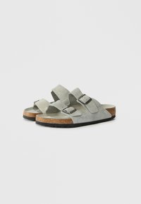 Γκρίζες σουέντ σάνταλες με δύο ρυθμιζόμενες λουρίδες, ασημένιες πόρπες και υφασμάτινη πλάκα από φελλό σε μαύρη καουτσούκ σόλα.