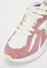 Pink suede and mesh sneaker with white accents and textured laces, featuring a rounded toe and padded tongue with branding detail.