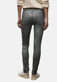 Höga grå stretchbyxor med smal passform, som har två bakfickor och subtila sömnadsdetaljer. Kombineras med ljusa sneakers.