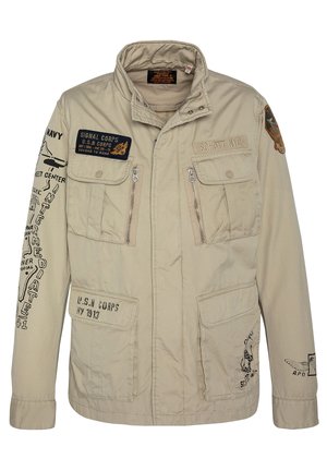 Beige militaire stijl jas met meerdere zakken, ritsen en verschillende geborduurde patches. Katoenen materiaal met een gladde textuur.
