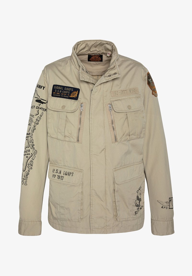 Beżowa kurtka w stylu militarnym z wieloma kieszeniami, zapięciami na zamek błyskawiczny i różnymi haftowanymi naszywkami. Wykonana z bawełny o gładkiej fakturze.