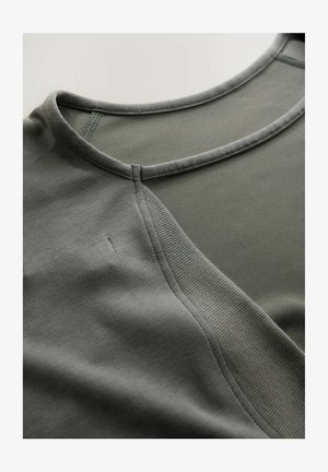 Nahaufnahme des grauen Sportbekleidungs-Halsausschnitts mit Rippstrick-Detail und verstärkter Naht.