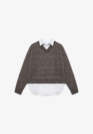 Pull en tricot marron avec un col en V, portant une chemise blanche en dessous. Le design comprend une longueur cropped et un tissu texturé.