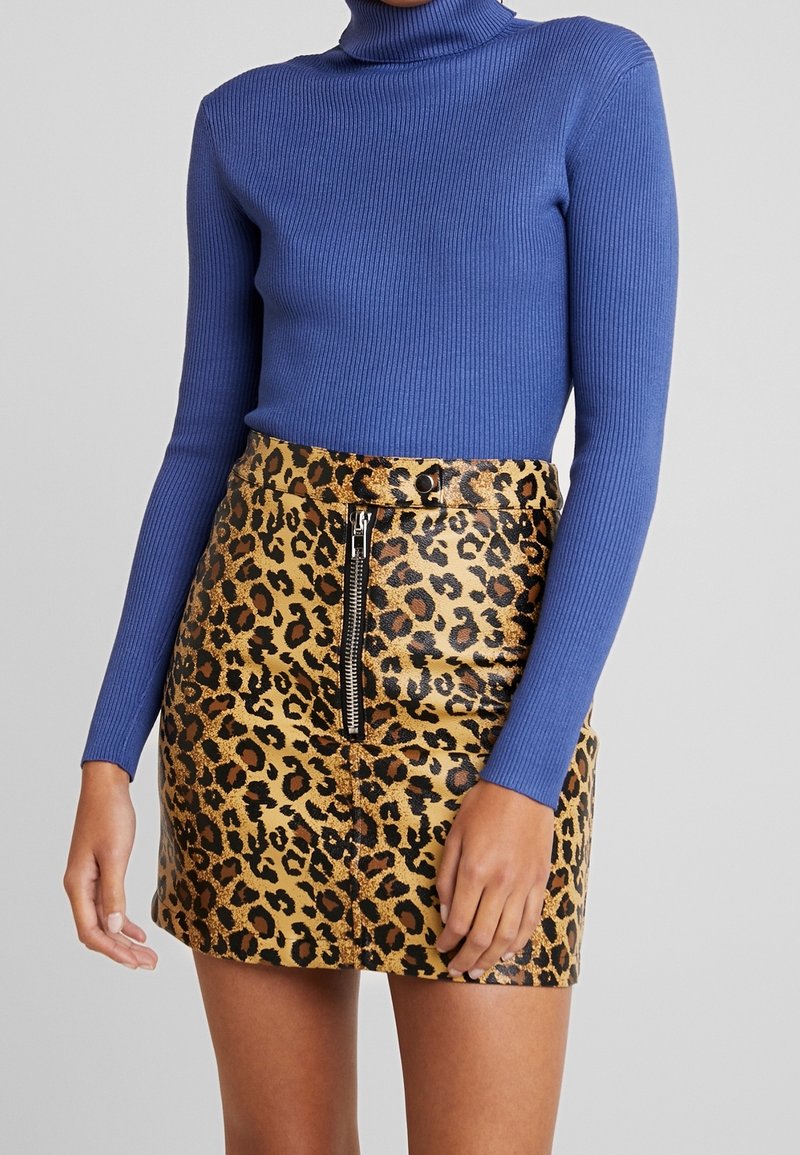 Maglione a collo alto blu a coste abbinato a una mini gonna leopardata a vita alta con zip frontale e finitura lucida.
