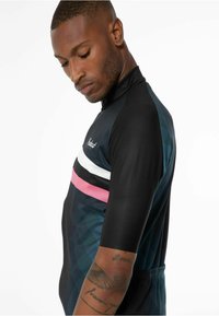 Krátký rukáv cyklistický dres v černé barvě s akcenty v tyrkysové a růžové. Má zipový uzávěr a geometrický vzor na látce.
