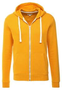 Sweat à capuche jaune avec fermeture éclair, fabriqué en tissu doux, comprenant une fermeture éclair à l'avant, des cordons blancs et deux poches avant. Poignets et ourlet côtelés.