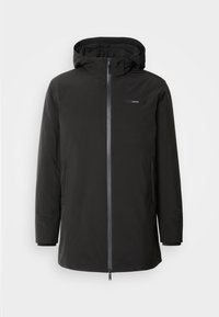 Veste à capuche noire en matériau doux et isolant. Elle dispose d'une fermeture éclair à l'avant, de poches latérales et d'un design minimaliste avec un petit logo.